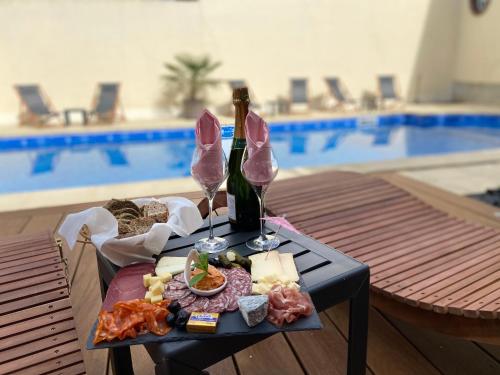 una mesa con una bandeja de comida y dos copas de vino en Au fil de l’Ô en Bisseuil