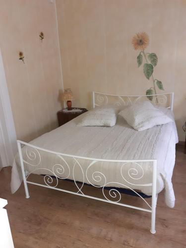ein Schlafzimmer mit einem weißen Bett mit einer Blume an der Wand in der Unterkunft la maison seillere in Senones