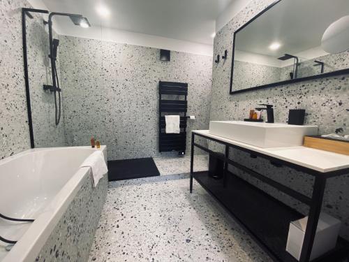 a bathroom with a tub and a sink and a mirror at Hôtel 16 | 150 Montagne & Spa Nuxe in Vars