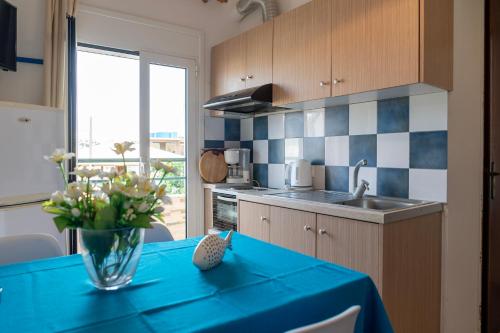 a kitchen with a blue table with a vase of flowers on it at La Stella Apartments in Amoudara Herakliou