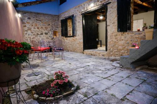 a stone patio with a table and chairs and flowers at Christi Iuxury Apartment in Preveza
