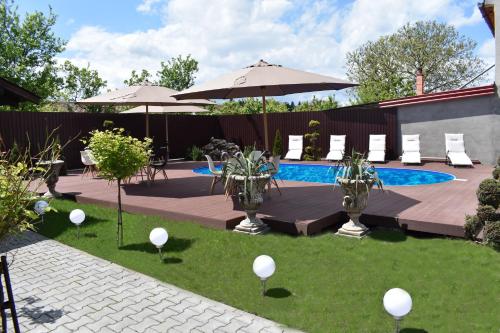 un patio trasero con piscina, sillas y sombrillas en Pensiunea Casa Zece, en Turda