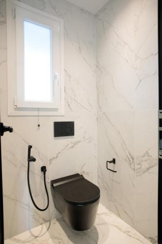 a bathroom with a black toilet and a window at Iphimedeia Luxury Hotel & Suites in Naxos Chora