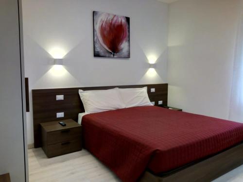 a bedroom with a red bed with a painting on the wall at Hotel Cajeta in Buia