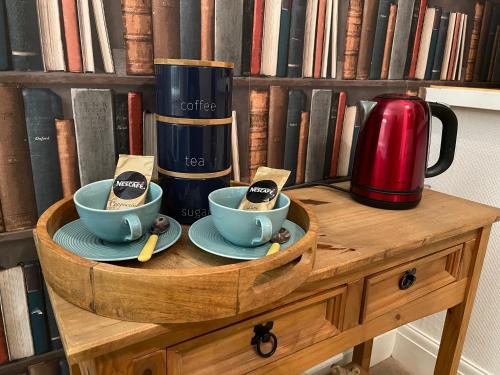 a wooden table with two tea cups and a coffee maker at G&T Apartment in Scarborough