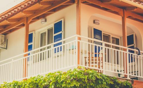 a house with a white balcony with blue shutters at Kiani Akti in Katelios