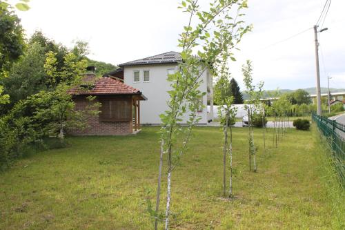 a row of trees in a yard next to a house at Nadia's home in Ilidža