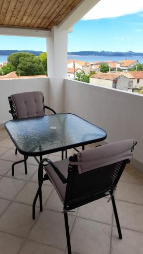 a glass table and two chairs on a balcony at Apartments Mira in Bibinje