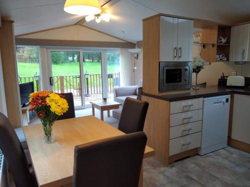 a kitchen with a table with a vase of flowers on it at Lazy Days Lodge in Glendevon