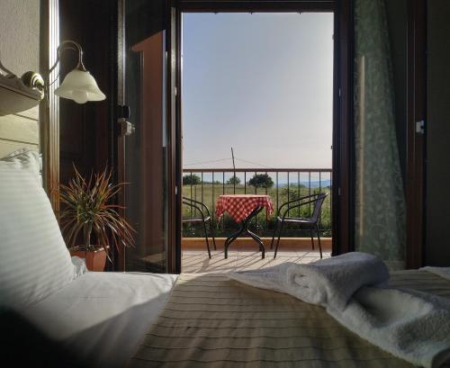 a bedroom with a bed and a balcony with a table at Geomelia Guest Studio 1 & Geomelia Guest Studio 2 in Polygryos