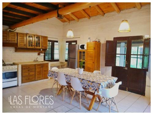 a kitchen with a table and white chairs in it at Las Flores, casa del valle in Potrerillos