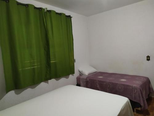 a room with two beds and green curtains at Quarto duplo aconchegante com banheiro privativo, ambiente inteiro in Barueri