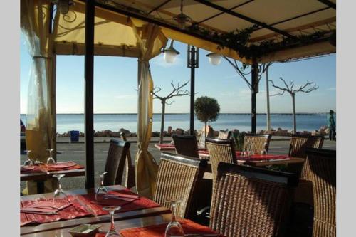a restaurant with tables and chairs and the beach at Superbe appartement avec Terrasse et Vue in Bouzigues