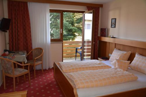 a hotel room with a bed and a table and a window at Kurpension Gundula in Bad Füssing