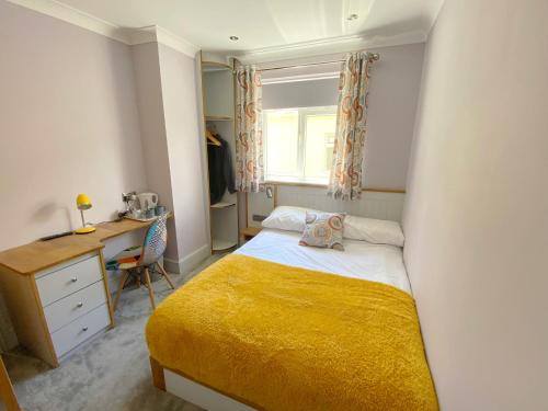 a small bedroom with a bed and a desk at Orchard House in Swindon
