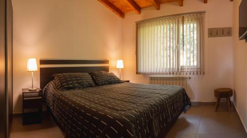ein Schlafzimmer mit einem Bett, zwei Lampen und einem Fenster in der Unterkunft Apartamentos del Sol in San Carlos de Bariloche