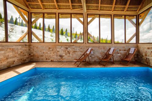 a room with a swimming pool with two chairs and windows at Domki Sówka in Dursztyn