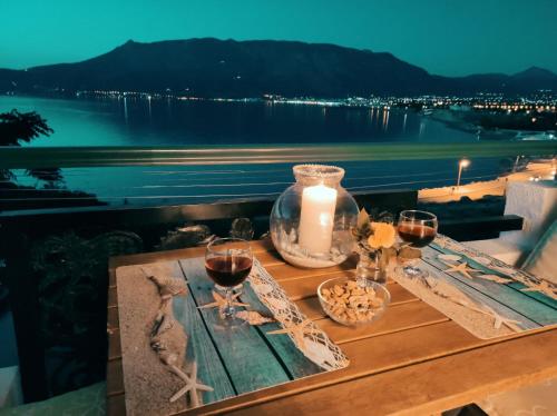 a table with two glasses of wine and a candle at Seaside Sunset in Korinthos