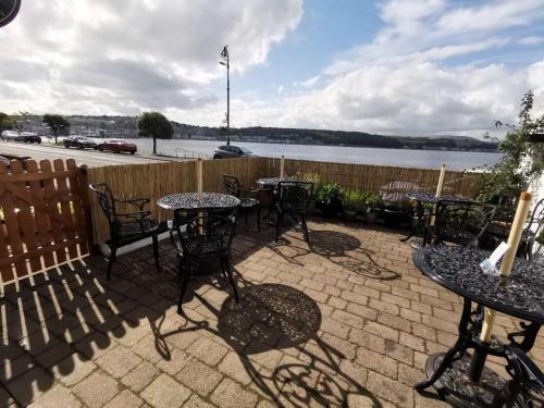 a patio with tables and chairs and a body of water at Summer's Bay in Rothesay
