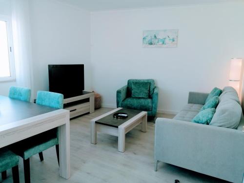 sala de estar con sofá, sillas y TV en Casa Doce, en Olhão