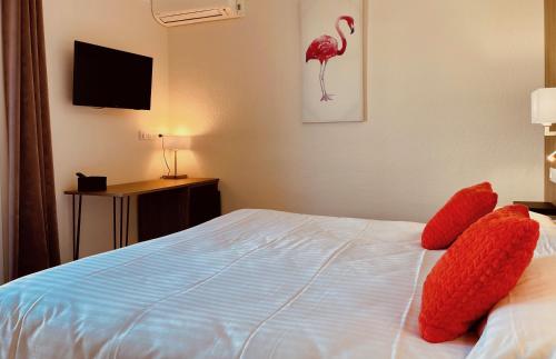 a bedroom with a bed with red pillows on it at Hotel Courbet in Juan-les-Pins