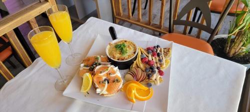 une table avec une assiette de nourriture et deux verres de jus d'orange dans l'établissement Orange Bistro, à Baie-Saint-Paul