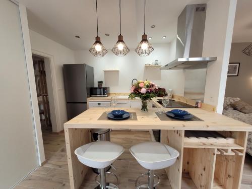 une cuisine avec un grand îlot en bois avec des tabourets blancs dans l'établissement Appartement charmant au cœur de la cité bragarde, à Saint-Dizier