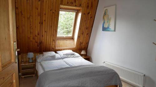 a bedroom with a bed with white sheets and a window at Pokoje DAJAN in Łeba