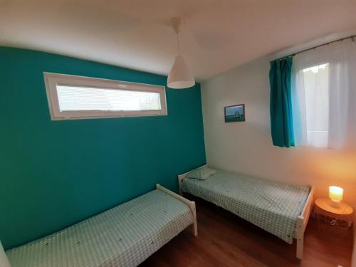 een groene kamer met 2 bedden en een raam bij Villa Aquamarine in Balatonboglár