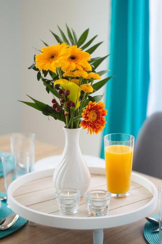 a vase of flowers and a glass of orange juice on a table at Villa Aquamarine in Balatonboglár
