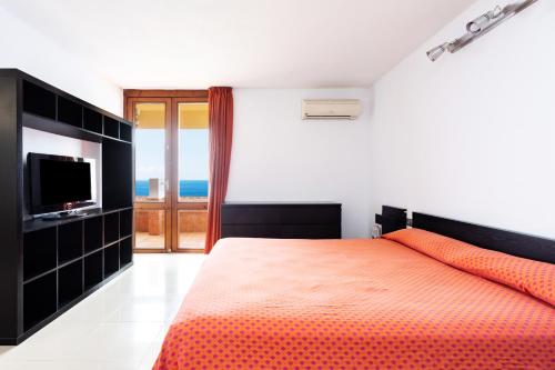 a bedroom with a bed with an orange bedspread and a television at Looking the VIEWS - 214 in Costa Del Silencio