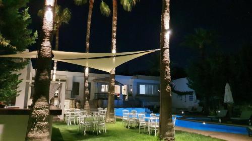 a group of tables and chairs by a pool at night at Elizabeth Suites in Kato Daratso