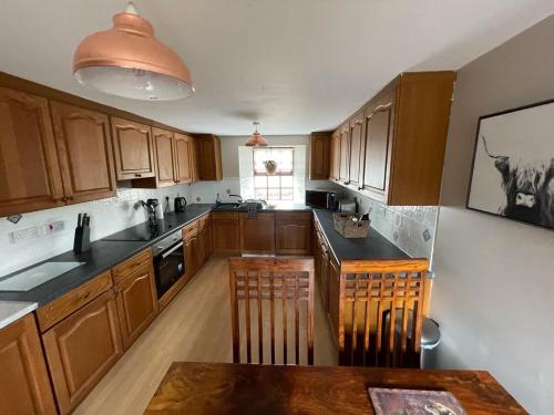 a kitchen with wooden cabinets and a table in it at Mawenyoupe in Lochgilphead
