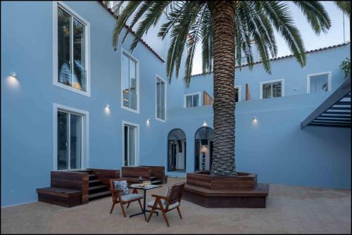 a palm tree in front of a building with a table and chairs at Casa do Pateo - Charming House Azores in Ponta Delgada