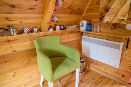 una silla verde en una habitación con paredes de madera en Cottage Borje en Žabljak