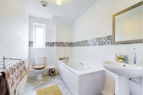 a bathroom with a tub and a sink and a toilet at Chic City Centre Apartment With Allocated Parking in Swansea