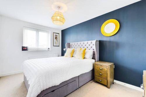 a blue bedroom with a large bed and a yellow mirror at Chic City Centre Apartment With Allocated Parking in Swansea