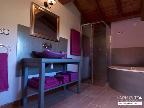 a bathroom with purple towels and a sink and a tub at Apartamentos Rurales La Pikurutza in Bernedo