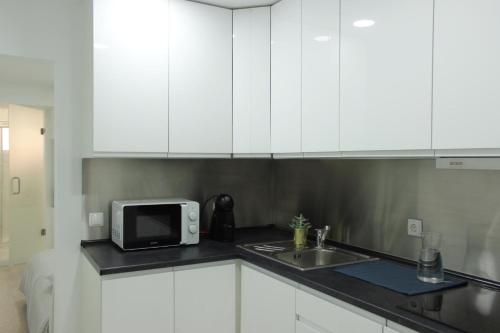 cocina con armarios blancos, fregadero y microondas en Nice and Cosy private apartment in Principe Real, Lisbon, en Lisboa