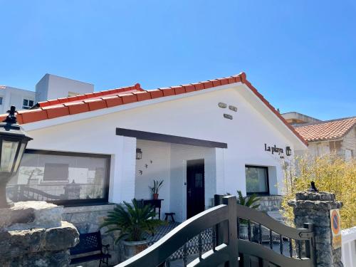 una casa blanca con una puerta y una valla en La Playa Suites Suances, en Suances