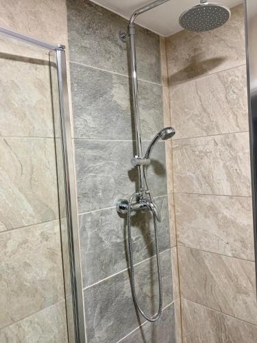 a shower stall with a glass door with a shower head at De Regency Style Hotel in Redditch