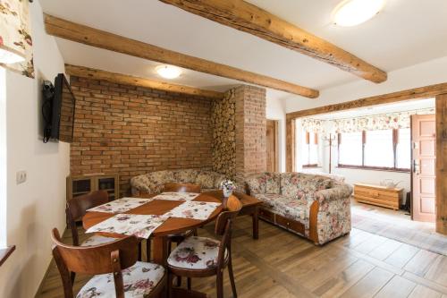 a living room with a table and chairs and a brick wall at Chalupa u Kova in Bešeňová