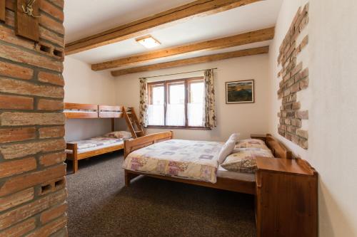 um quarto com 2 camas e uma parede de tijolos em Chalupa u Kova em Bešeňová