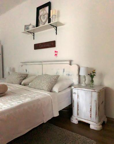 a bedroom with a white bed and a side table at Gyere be Vendégház in Drégelypalánk