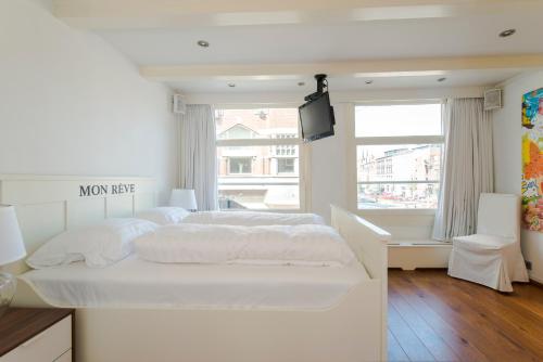 a white bedroom with a white bed and a television at B&B The Catch Apartment in Amsterdam
