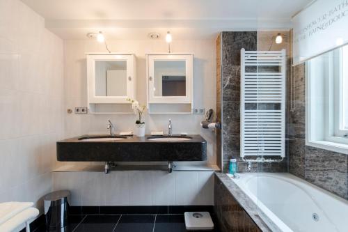 a bathroom with two sinks and a bath tub at B&B The Catch Apartment in Amsterdam