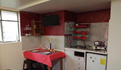 a small kitchen with red cabinets and a red table at Mini suites en el mejor sector de la ciudad in Quito