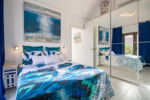 Un dormitorio con una cama azul y blanca y un espejo en Bungalow Portos with amazing privet garden, en Playa del Inglés