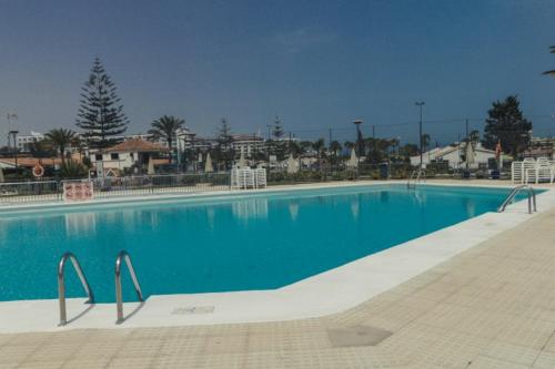 Una gran piscina con agua azul en un complejo turístico. en Bungalow Portos with amazing privet garden, en Playa del Inglés