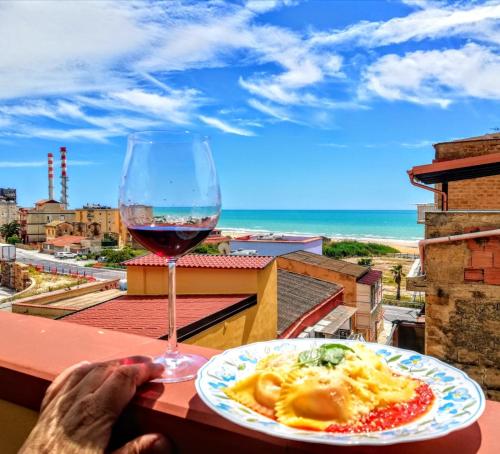 un plato de comida y una copa de vino en una mesa en Casa Vacanza Nonna Nena, en Porto Empedocle
